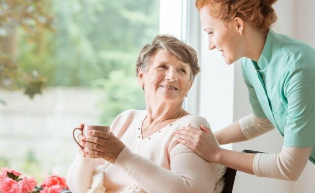 professional caretaker in uniform helping a geriatric female patient on a wheelchair