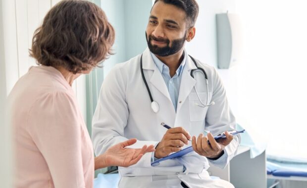 male doctor consulting senior old patient filling form at consultation