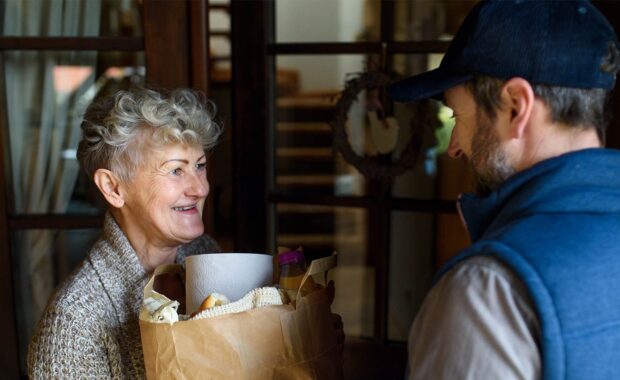 young delivery driver handing over delivery order to elderly women