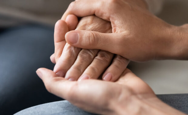 young woman holding female hand of older mother