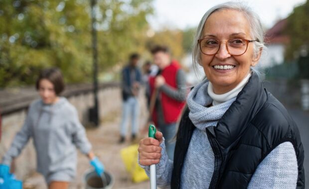 senior woman volunteer with team cleaning up street