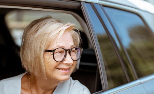 happy senior business woman looking out the car window
