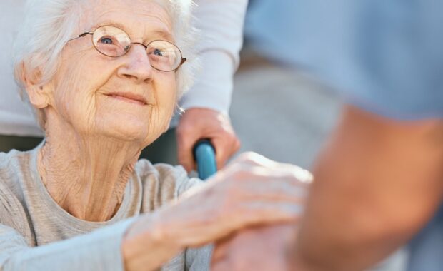 caregiver and senior woman in wheelchair for support outdoor in retirement home
