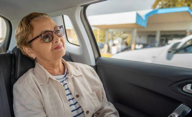 senior woman sitting in the passenger seat in the car enjoying the ride