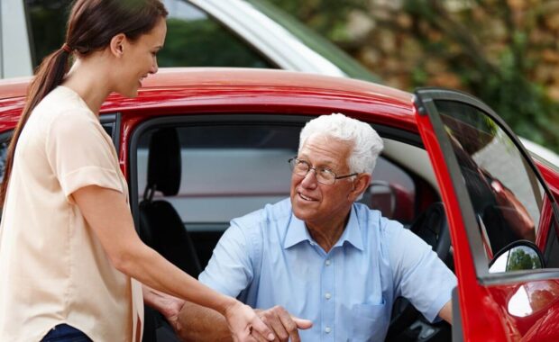 woman helping her senior father out of the car