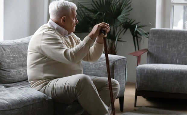 mature male with grey hair resting on sofa leaning on stick in Northern VA