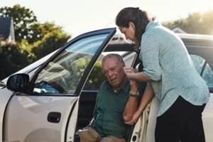 shot of a woman helping her senior father out the car
