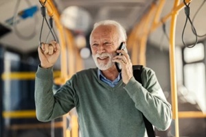 portrait of a smiling old passenger commuting by public city bus and having phone call