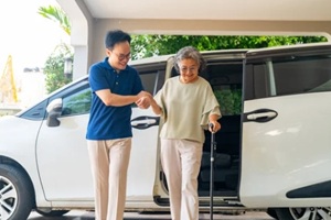 asian man taking his mother out from a car