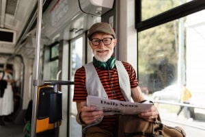 Elderly Man Reading News Paper While Traveling in Bus