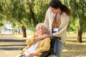 young african-american female medical worker with elderly woman on wheelchair outdoors
