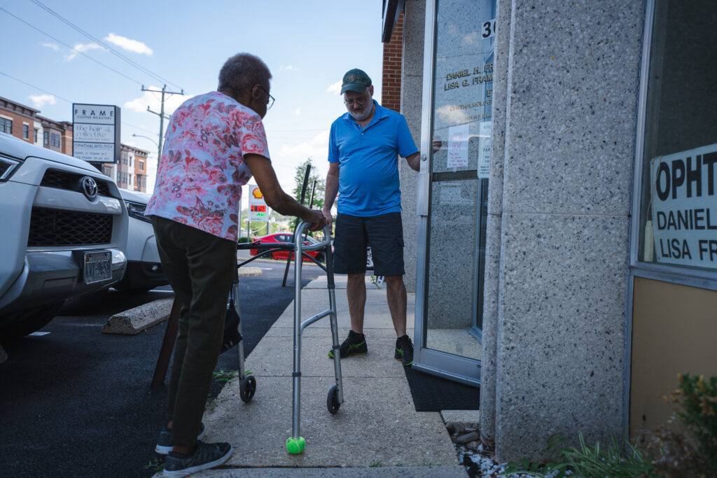 SCNOVA volunteer Wolfie opens the door for his passenger participant, Lalita, in front of the doctor's office.