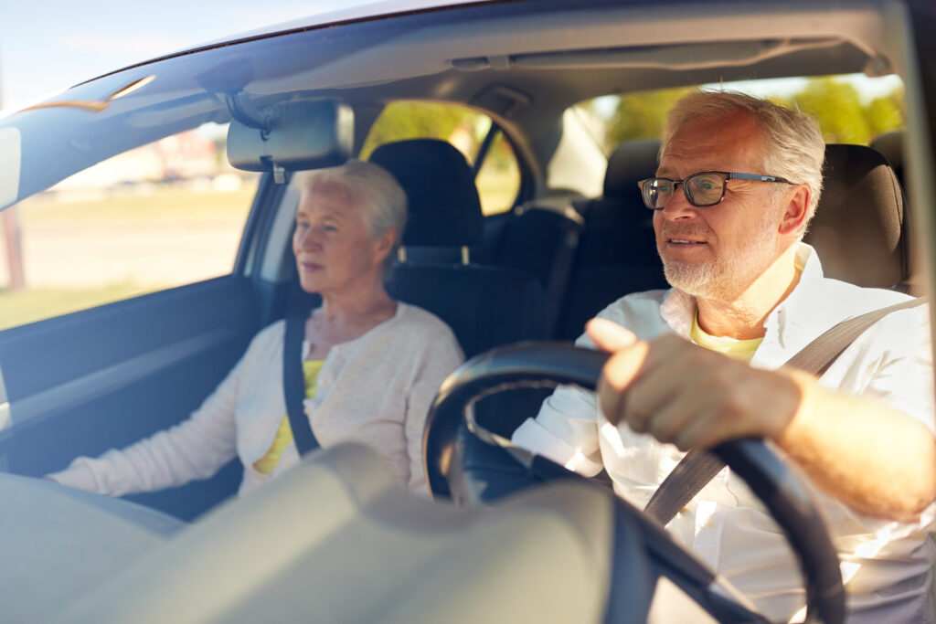 an older adult male driving an older adult female in a car