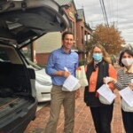 Man and two women wearing masks holding up food for charity