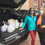 women with masks next to food in back of car
