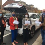 group holding food behind white car